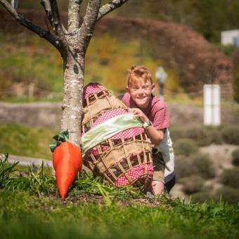 Boy peeping out from behind a willow woven Easter egg